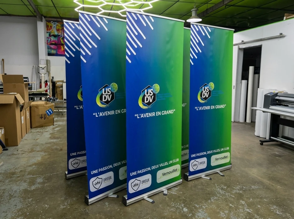Atelier d'impression, trois roll-up banners identiques exposés en ligne sur socles aluminium rétractables